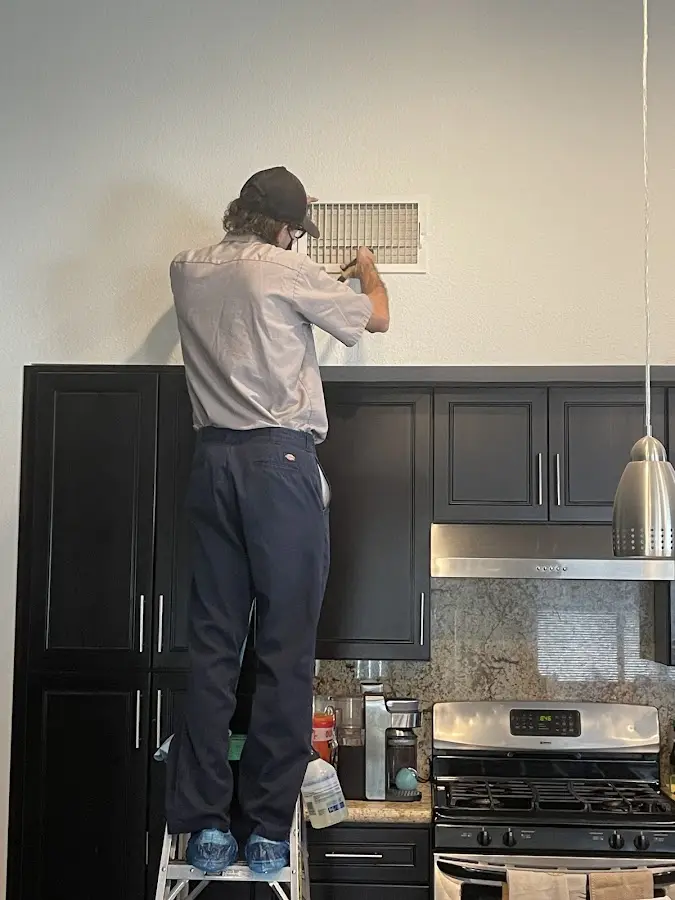 Technician inspecting an air vent during HVAC service in Sunnyside